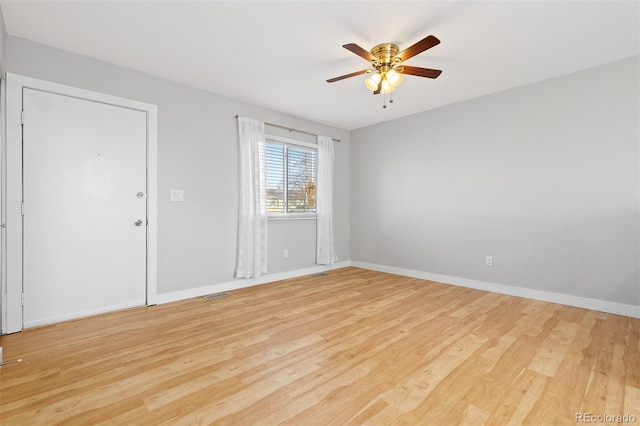 unfurnished room with a ceiling fan, visible vents, light wood-style flooring, and baseboards