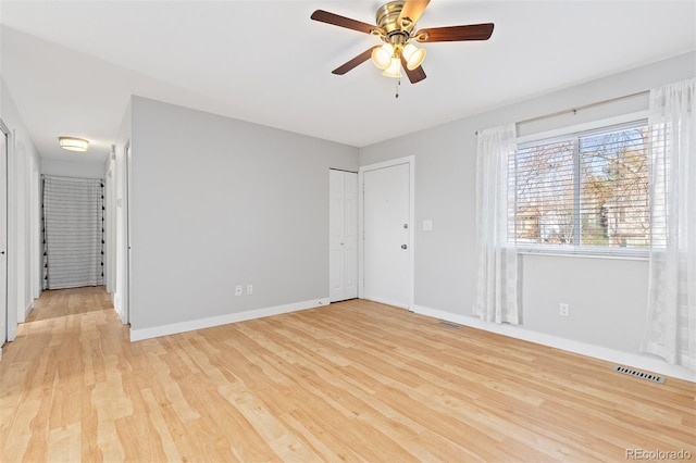 unfurnished bedroom featuring light wood-style flooring, a ceiling fan, visible vents, and baseboards