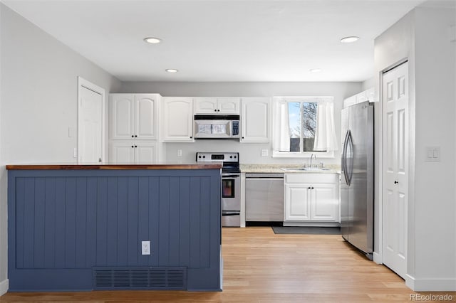 kitchen featuring visible vents, appliances with stainless steel finishes, white cabinets, and a sink