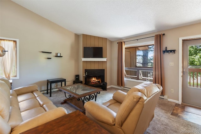 401 Forest Edge Rd Unit B2, Woodland Park, CO 80863 - living room with a lit fireplace, lofted ceiling, a baseboard heating unit, and a textured ceiling