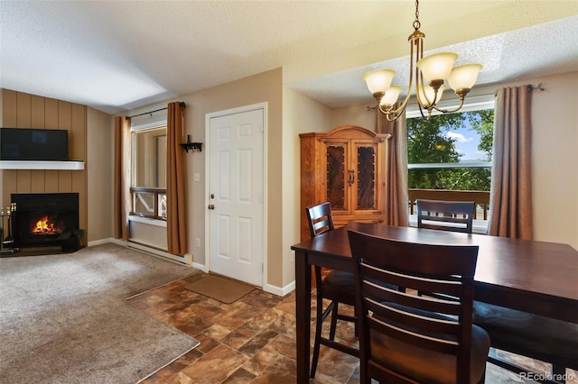 401 Forest Edge Rd Unit B2, Woodland Park, CO 80863 - dining space with a textured ceiling, a chandelier, a baseboard heating unit, a lit fireplace, and dark stone finish flooring