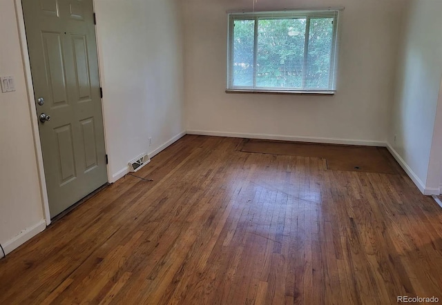 spare room with visible vents, baseboards, and hardwood / wood-style flooring