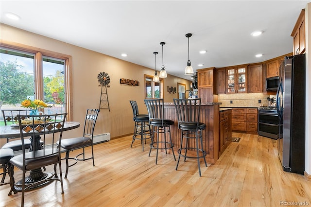 kitchen featuring a kitchen island, appliances with stainless steel finishes, a breakfast bar, pendant lighting, and light hardwood / wood-style floors