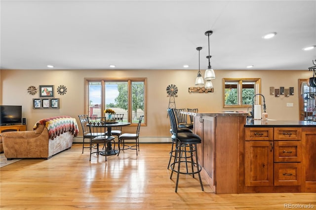 kitchen with a breakfast bar, a healthy amount of sunlight, light hardwood / wood-style flooring, and pendant lighting