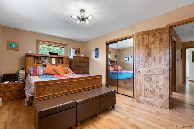 bedroom with a closet, light hardwood / wood-style floors, and an inviting chandelier