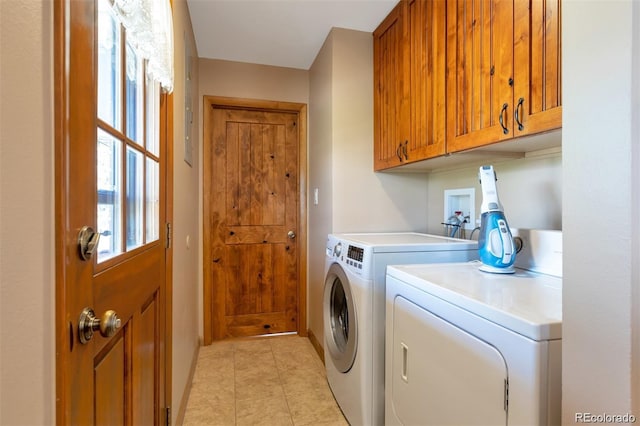 clothes washing area featuring washer and dryer, light tile patterned flooring, and cabinets