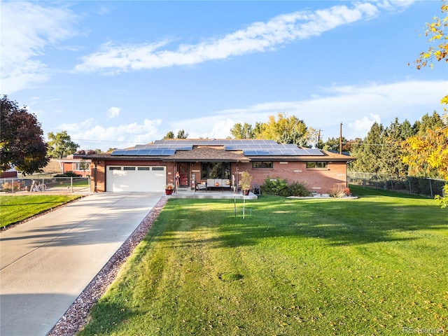 view of front of home featuring a front yard, solar panels, and a garage