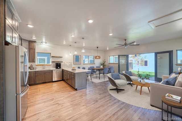 kitchen with sink, pendant lighting, light hardwood / wood-style floors, decorative backsplash, and appliances with stainless steel finishes