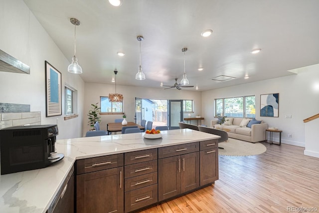 kitchen featuring decorative light fixtures, light hardwood / wood-style flooring, ceiling fan, light stone countertops, and dark brown cabinets