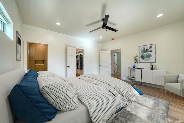 bedroom with ceiling fan, light hardwood / wood-style floors, a spacious closet, and a closet