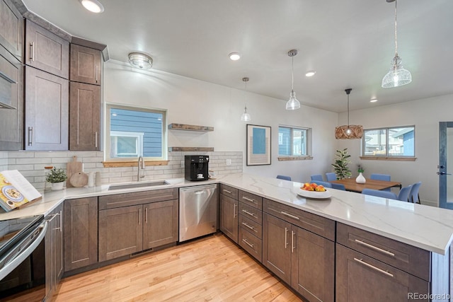 kitchen featuring decorative light fixtures, kitchen peninsula, sink, and appliances with stainless steel finishes