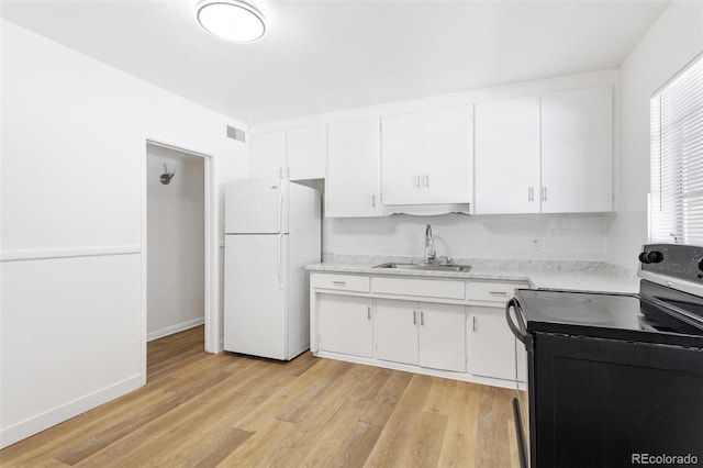 kitchen with stainless steel electric range oven, freestanding refrigerator, light countertops, white cabinetry, and a sink