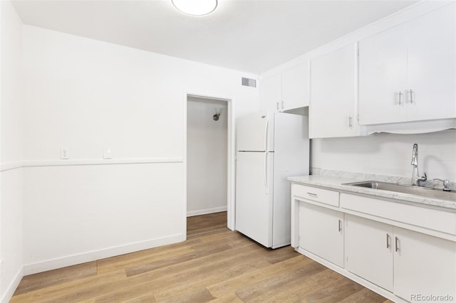 kitchen with light countertops, visible vents, freestanding refrigerator, white cabinetry, and a sink