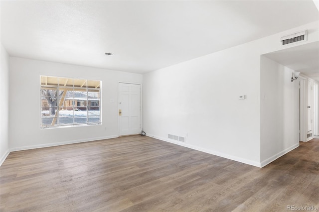 empty room with visible vents, baseboards, and wood finished floors