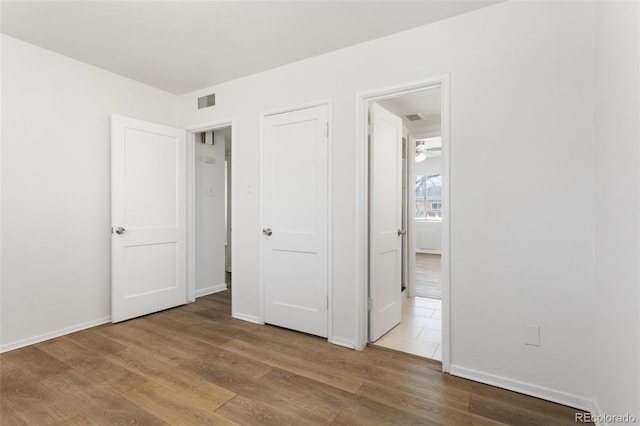 unfurnished bedroom featuring visible vents, baseboards, and wood finished floors