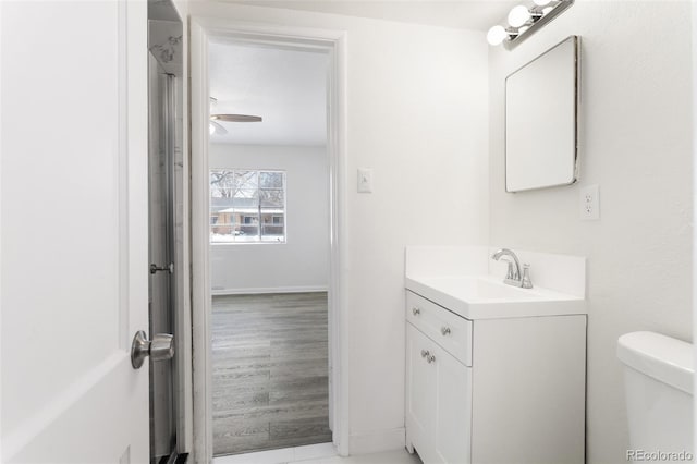 bathroom with baseboards, vanity, toilet, and wood finished floors