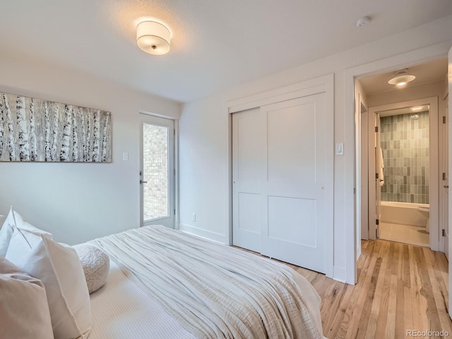 bedroom featuring ensuite bathroom, light hardwood / wood-style flooring, and a closet