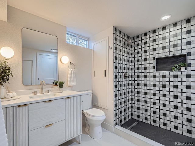 bathroom with tile patterned flooring, vanity, toilet, and a tile shower