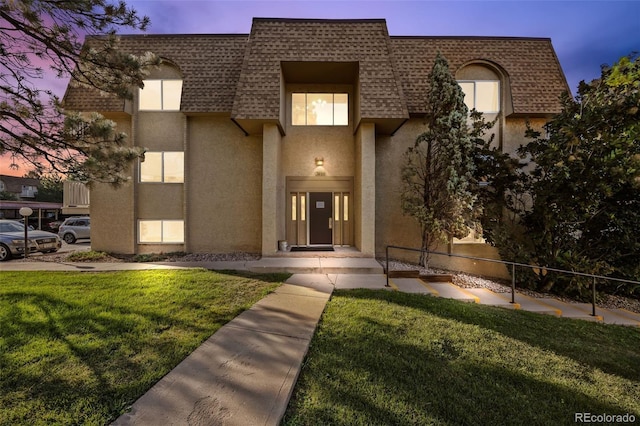 7495 E Quincy Ave Unit 208, Denver, CO 80237 - view of front of house featuring mansard roof, roof with shingles, stucco siding, and a front yard