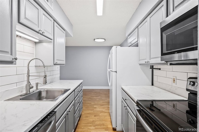 7495 E Quincy Ave Unit 208, Denver, CO 80237 - kitchen featuring appliances with stainless steel finishes, gray cabinetry, decorative backsplash, and light wood-style floors