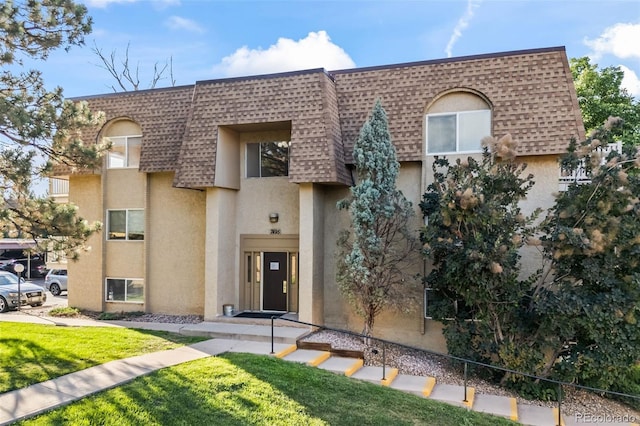 7495 E Quincy Ave Unit 208, Denver, CO 80237 - view of front of property with mansard roof, a shingled roof, stucco siding, and a front yard