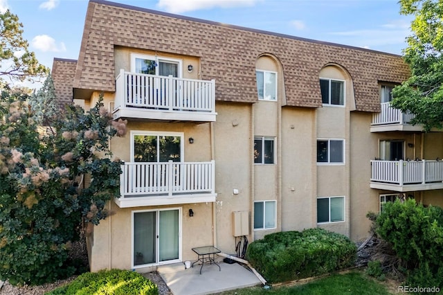 7495 E Quincy Ave Unit 208, Denver, CO 80237 - rear view of house featuring roof with shingles, mansard roof, a balcony, and stucco siding