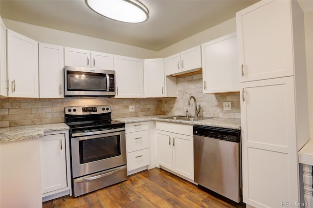 kitchen with appliances with stainless steel finishes, backsplash, a sink, and white cabinetry