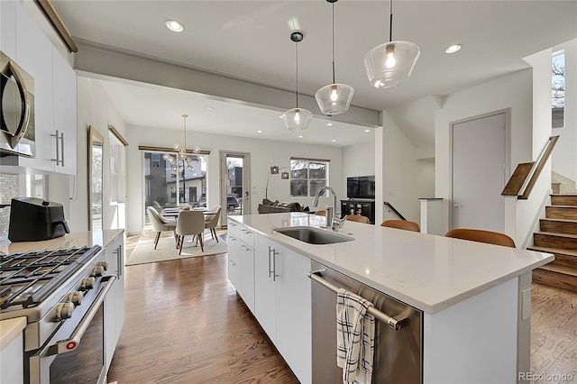 kitchen with dark wood finished floors, white cabinets, an island with sink, pendant lighting, and a sink