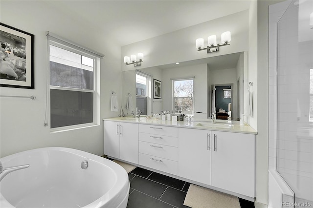 bathroom featuring double vanity, a sink, tile patterned floors, and a soaking tub