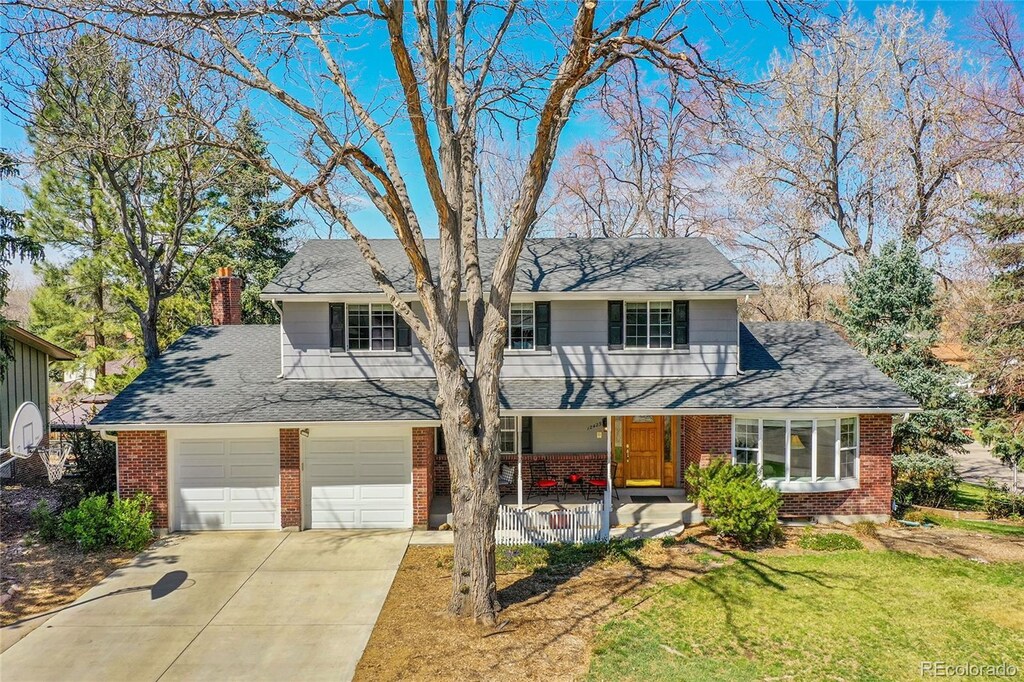 12423 W 68th Ave, Arvada, CO 80004 - traditional-style house with brick siding, a porch, a front yard, and concrete driveway