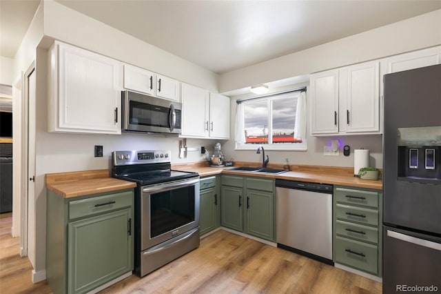 kitchen with white cabinetry, sink, stainless steel appliances, and light hardwood / wood-style floors