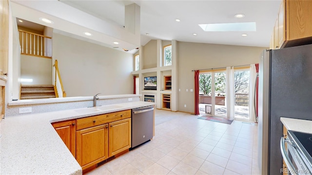 kitchen with a skylight, stainless steel appliances, recessed lighting, light countertops, and a sink