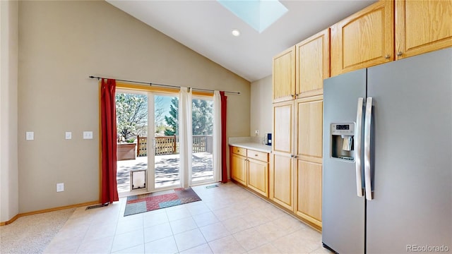 kitchen featuring light brown cabinets, a skylight, baseboards, light countertops, and stainless steel fridge