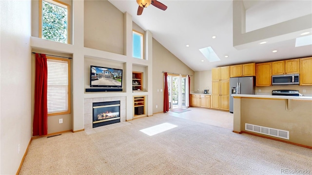 unfurnished living room with light colored carpet, a skylight, visible vents, and a tiled fireplace