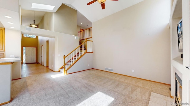 unfurnished living room with stairway, visible vents, high vaulted ceiling, and light colored carpet