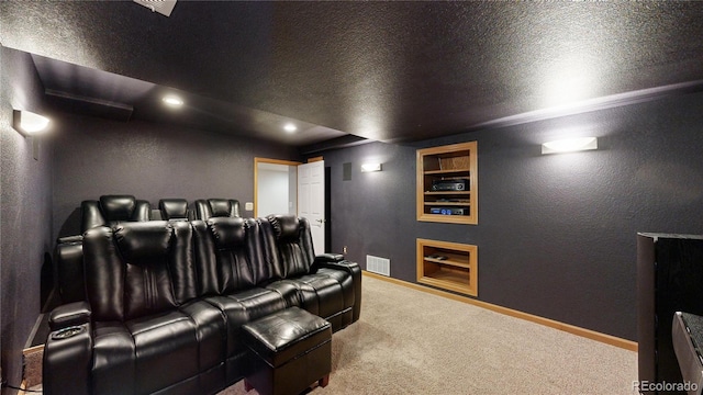 carpeted cinema room featuring baseboards, visible vents, a textured ceiling, and a textured wall