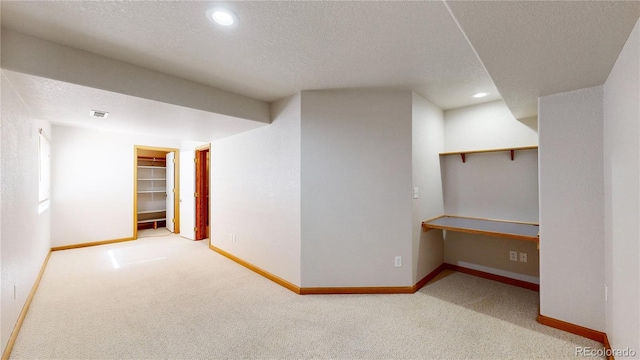 finished basement featuring a textured ceiling, recessed lighting, carpet floors, baseboards, and built in study area