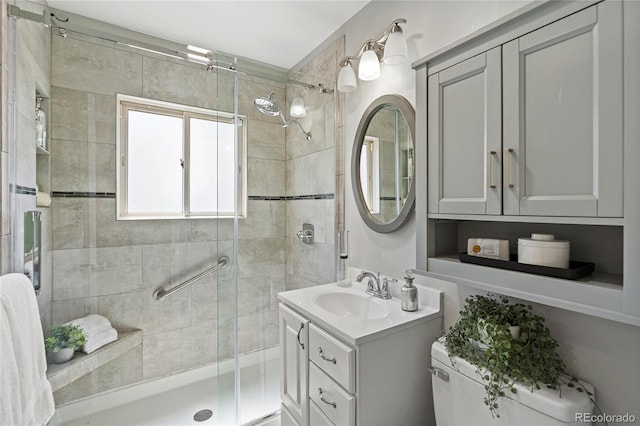 bathroom featuring vanity, a shower with shower door, and toilet