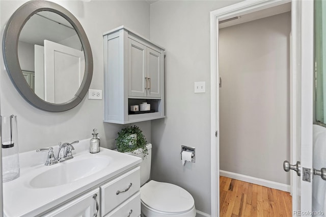 bathroom with toilet, hardwood / wood-style flooring, and vanity