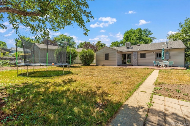 view of yard with a trampoline, a patio, and central AC unit