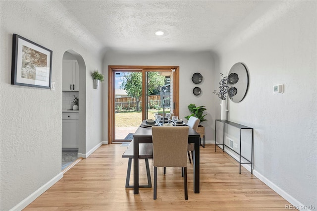 dining area with a textured ceiling and light wood-type flooring