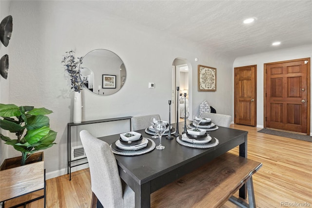 dining space with a textured ceiling and light hardwood / wood-style flooring