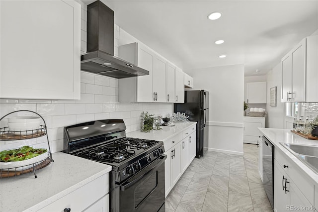 kitchen with washer / dryer, wall chimney range hood, black appliances, backsplash, and white cabinets