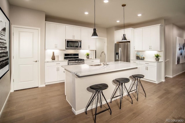 kitchen featuring a sink, tasteful backsplash, stainless steel appliances, a breakfast bar area, and dark wood-style flooring