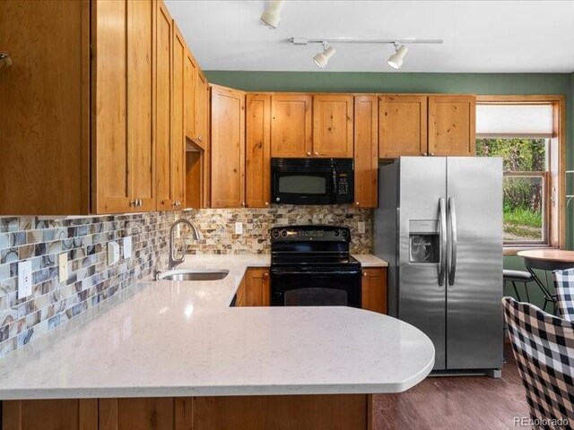 10000 Ryan Gulch Rd Unit 116, Silverthorne, CO 80498 - kitchen with black appliances, a peninsula, decorative backsplash, and dark wood finished floors