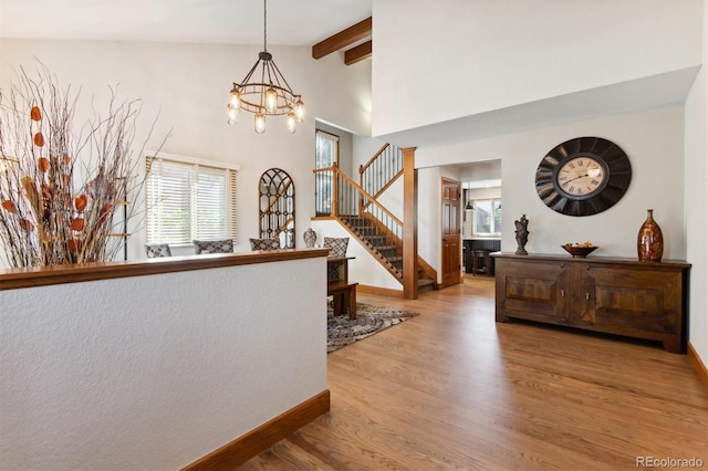 hallway with light hardwood / wood-style flooring, vaulted ceiling with beams, and a chandelier