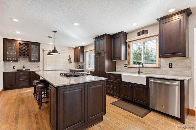 kitchen featuring sink, decorative light fixtures, light hardwood / wood-style flooring, a kitchen island, and appliances with stainless steel finishes