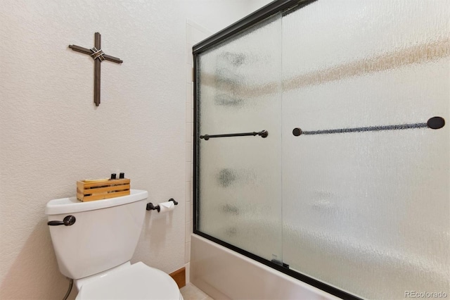 bathroom featuring combined bath / shower with glass door and toilet