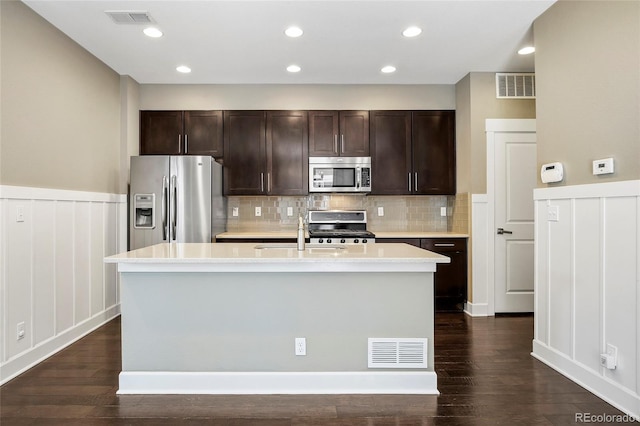 3450 Valentia St, Denver, CO 80238 - kitchen with stainless steel appliances, light countertops, dark brown cabinets, a kitchen island with sink, and wainscoting