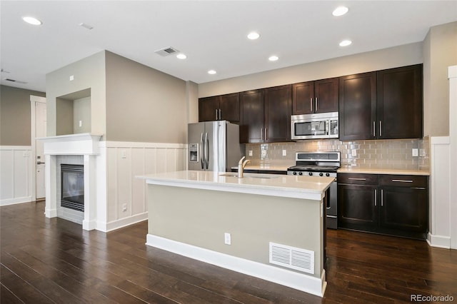 3450 Valentia St, Denver, CO 80238 - kitchen with stainless steel appliances, a sink, light countertops, a wainscoted wall, and dark wood finished floors
